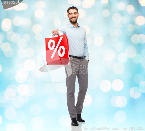 Image of smiling man with red shopping bag over blue lights