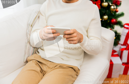 Image of smiling man with smartphone at home for christmas