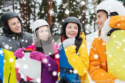 Image of happy friends in helmets with snowboards talking