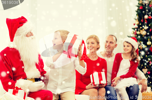 Image of smiling family with santa claus and gifts at home