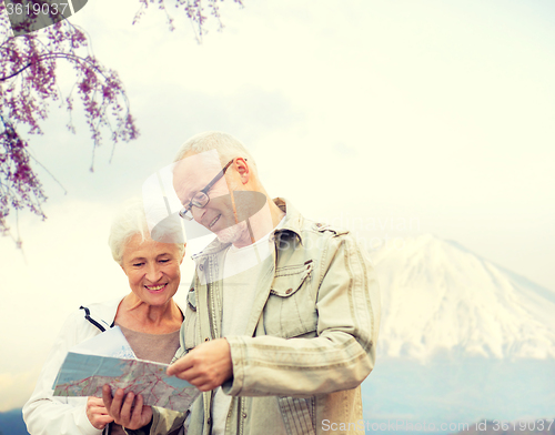 Image of happy senior couple with travel map over mountains