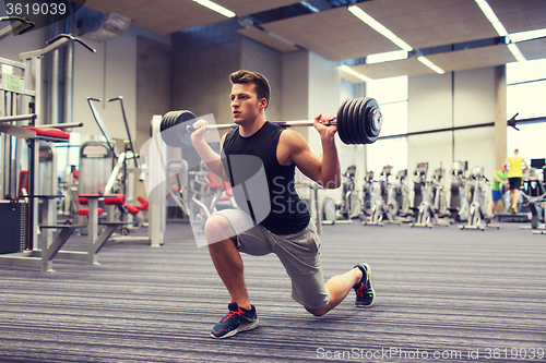 Image of young man flexing muscles with barbell in gym