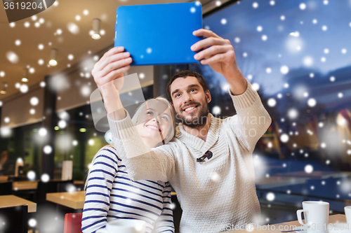Image of happy couple with tablet pc taking selfie at cafe