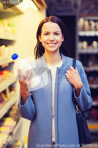 Image of happy woman holding milk bottle in market