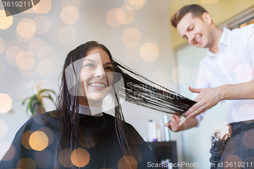 Image of happy woman with stylist cutting hair at salon