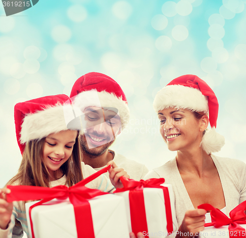 Image of happy family in santa helper hats with gift boxes