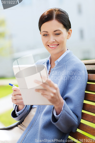 Image of businesswoman reading notes in notepad outdoors