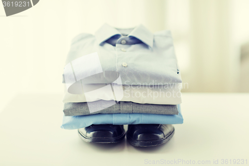 Image of close up of folded male shirts and shoes on table