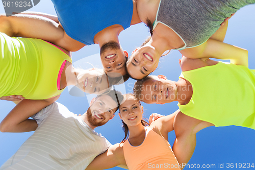 Image of group of happy sporty friends in circle outdoors