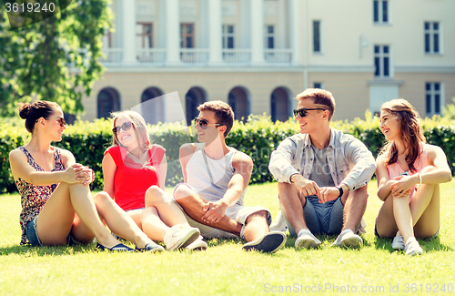 Image of group of smiling friends outdoors sitting on grass