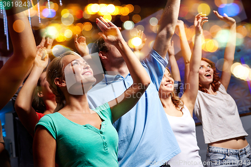 Image of smiling friends at concert in club