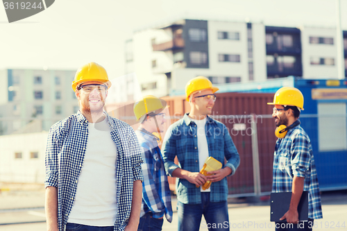 Image of group of smiling builders in hardhats outdoors