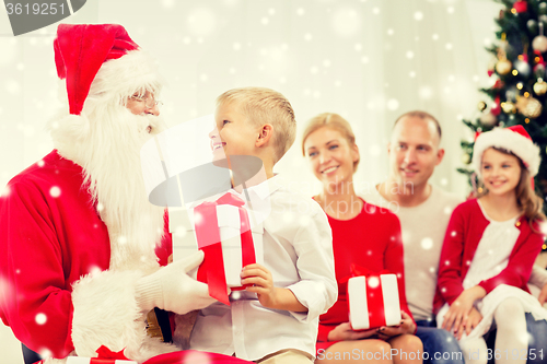 Image of smiling family with santa claus and gifts at home