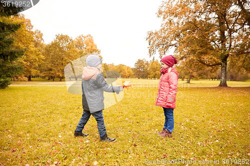 Image of little boy giving autumn maple leaves to girl