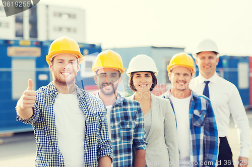 Image of group of smiling builders in hardhats outdoors