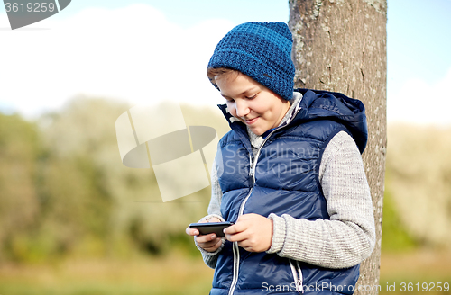Image of happy boy playing game on smartphone outdoors