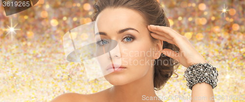 Image of beautiful woman with bracelet over golden lights