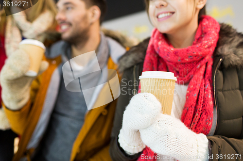 Image of happy friends with coffee cups on skating rink