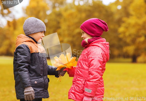 Image of little boy giving autumn maple leaves to girl