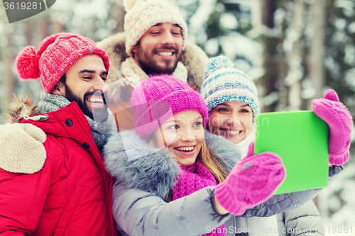 Image of smiling friends with tablet pc in winter forest