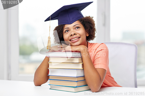 Image of happy african bachelor girl with books at home