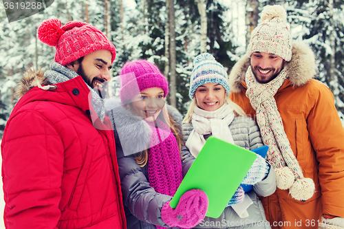 Image of smiling friends with tablet pc in winter forest
