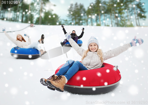 Image of group of happy friends sliding down on snow tubes