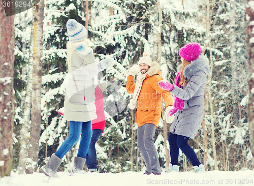 Image of group of happy friends playing snowballs in forest