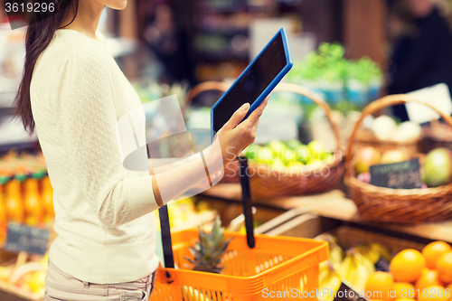 Image of woman with basket and tablet pc in market