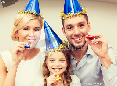 Image of smiling family in blue hats blowing favor horns