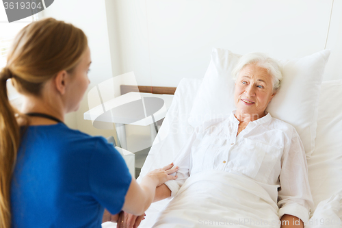 Image of doctor or nurse visiting senior woman at hospital