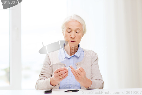 Image of senior woman with glucometer checking blood sugar