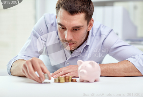 Image of businessman with piggy bank and coins at office