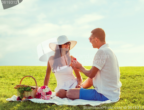 Image of smiling couple with small red gift box on picnic