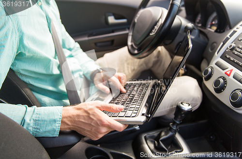 Image of close up of young man with laptop driving car