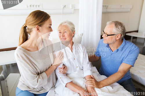 Image of happy family visiting senior woman at hospital