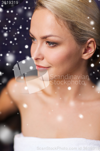 Image of beautiful woman sitting in bath towel at sauna