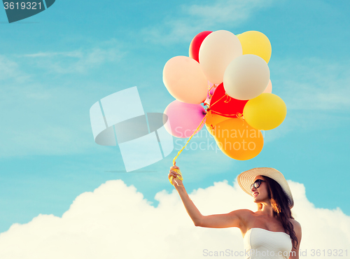 Image of smiling young woman in sunglasses with balloons