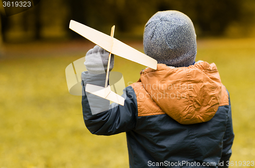 Image of happy little boy playing with toy plane outdoors