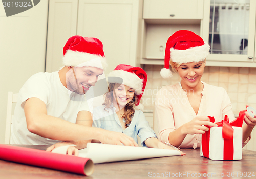 Image of smiling family in santa helper hats with gift box