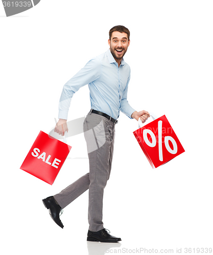 Image of smiling man walking with red shopping bag