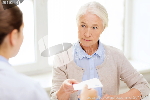 Image of doctor giving prescription to senior woman