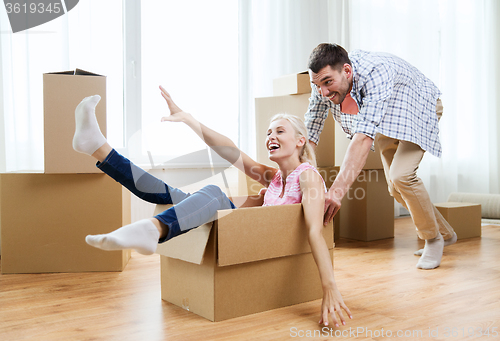 Image of couple with cardboard boxes having fun at new home