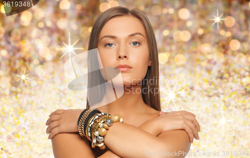 Image of beautiful woman with bracelets over golden lights