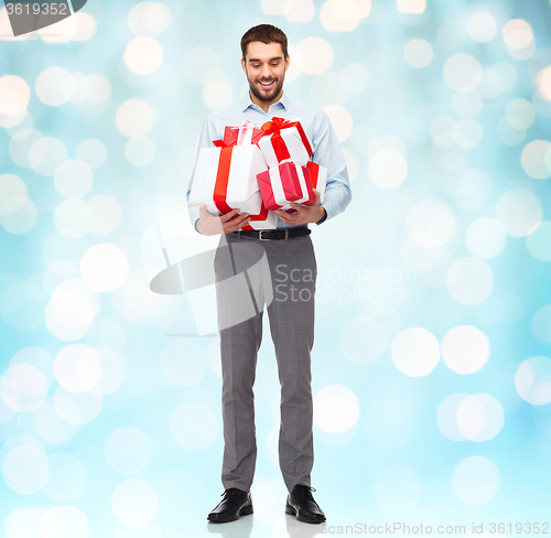 Image of happy young man holding gift boxes