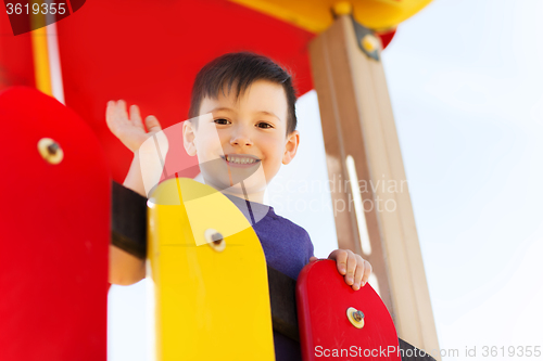 Image of happy little boy climbing on children playground