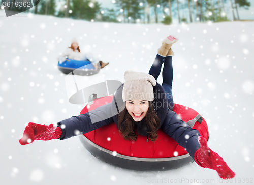 Image of group of happy friends sliding down on snow tubes