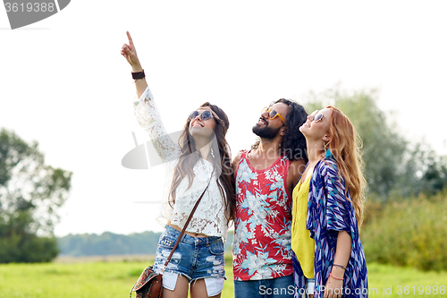 Image of happy hippie friends pointing finger outdoors