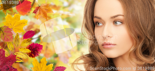 Image of beautiful young woman face over autumn leaves
