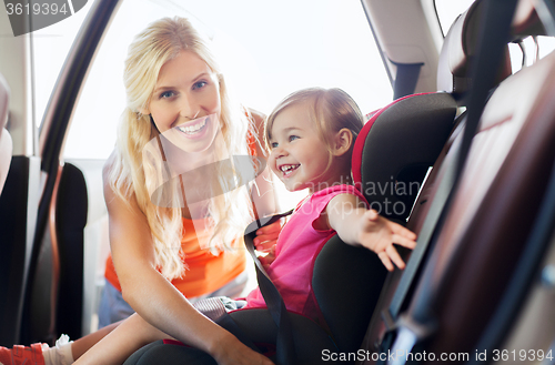 Image of happy mother fastening child with car seat belt